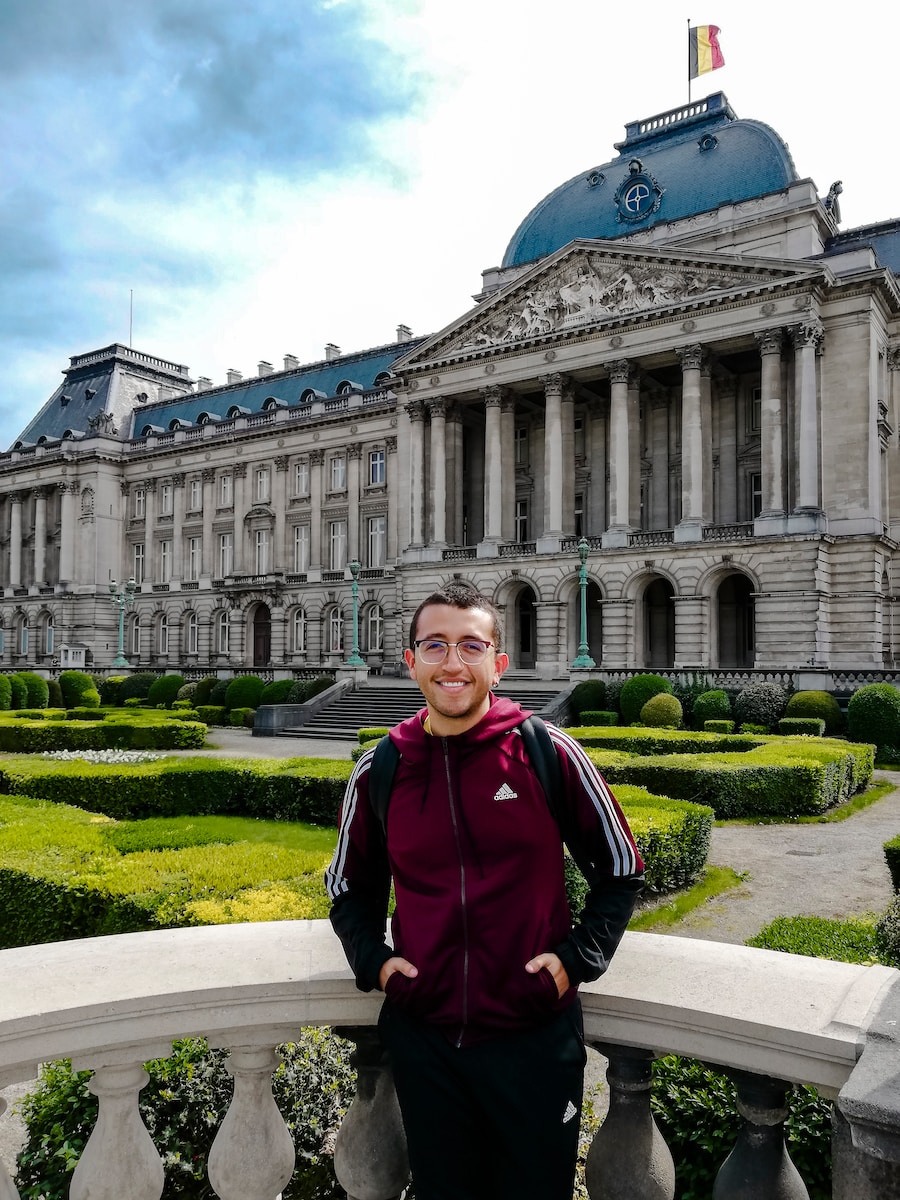 man in maroon adidas jacket standing beside concrete rail